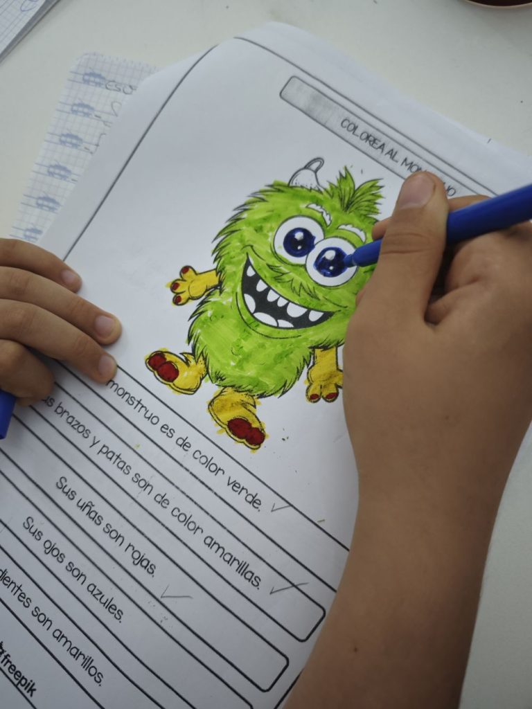 Niño coloreando un monstruo verde en una ficha