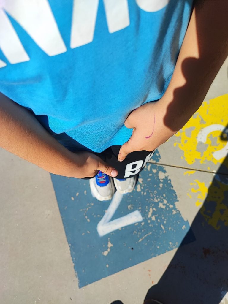 Niño saltando en una rayuela pintada en el suelo del patio